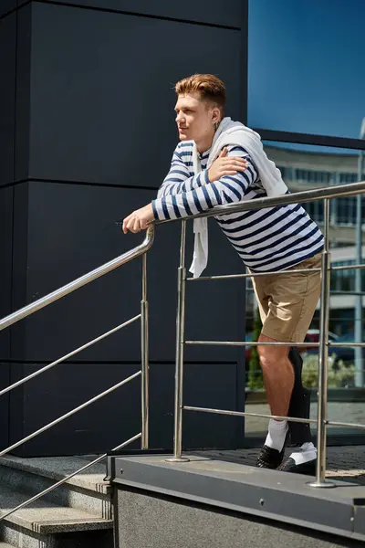 stock image A young man leans casually against a railing, showcasing his prosthetic leg while enjoying the day.