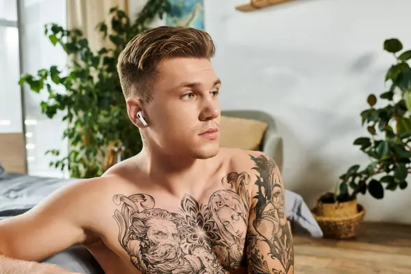 stock image In a serene indoor setting, a young man with a tattooed torso showcases his determination.