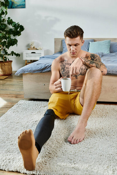 Сидя в уютной комнате, молодой человек с протезной ногой созерцает жизнь, потягивая чай.