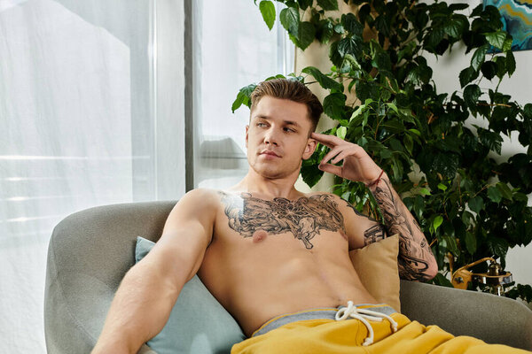 Молодой человек без рубашки, с боди-артом, наслаждается моментом созерцания в помещении.