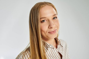 Kendine güvenen bir kadın zarif bir şekilde çizgili gömleğiyle uzun, dalgalı saçlarını sergiliyor..