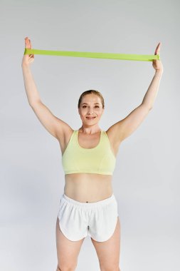 Kendini işine adamış bir sporcu kadın, bir direniş bandıyla enerjik bir egzersiz yapıyor, pozitif enerji yayıyor..