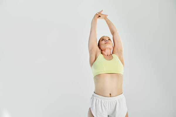 Решительная женщина демонстрирует свою силу и изящество, растягиваясь в яркой студии..