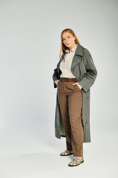 Красивая женщина уверенно позирует в шикарной осенней одежде, демонстрируя свои длинные волосы и стильный ансамбль.