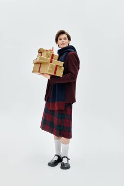 Minimalist bir mekanda zarif kış kıyafetleri içindeki bir kadın zarif hediyeler sunar..