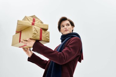 Güzel kadın zarif bir kış elbisesi giyer ve elinde gülümsemeli bir hediye kutusu taşır..