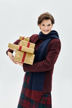 Kadın, güzel paketlenmiş hediyeleri arka planda tutarken sıcaklık ve neşe saçıyor..