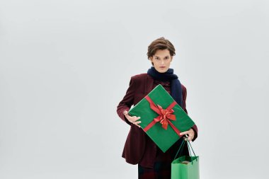 Kadın, şenlikli hediyeler taşırken sıcacık kış giysileriyle güzellik saçıyor..