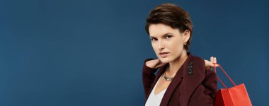 Zarif giyinmiş bir kadın, şık bir kış tarzı sergileyen alışveriş çantalarını tutuyor..