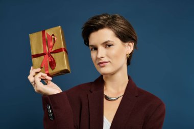 Kadın coşkulu bir kurdeleyle süslenmiş bir bayram hediyesini sunarken sıcakkanlı ve stil sahibi..