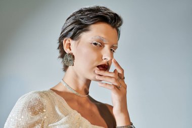 Zarif bir kadın zarif pozlar veriyor, şık kış kıyafetlerini hafif ışıklandırmayla sergiliyor.