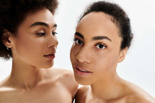 Two women share a moment of connection, showcasing their unique beauty and expressions.