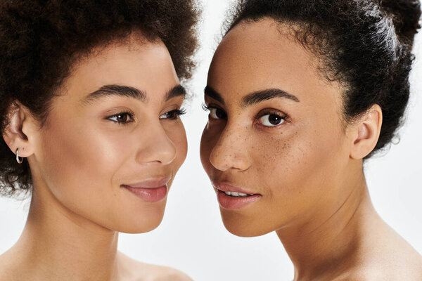 Two women share a serene moment, showcasing their unique features and confidence.