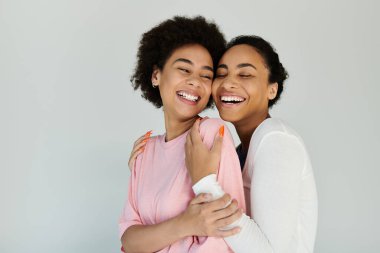 Two friends share a warm embrace while laughing, showcasing their happiness and connection. clipart