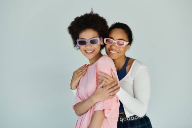 İki arkadaş, basit bir arkaplana karşı samimi bir anda kahkaha ve neşeyi paylaşıyor..