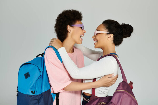 Two friends embrace, sharing joyful laughter and fashionable styles in a vibrant studio.
