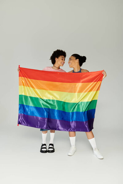 Two friends share a heartfelt moment holding a rainbow flag, symbolizing pride and community.