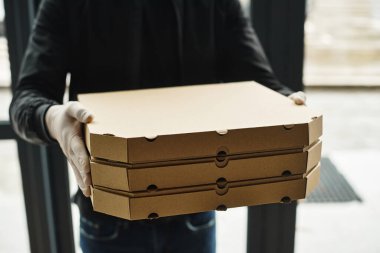 Eldiven giyen bir teslimatçı düzgün istiflenmiş kutuları ofis düzenine taşır..