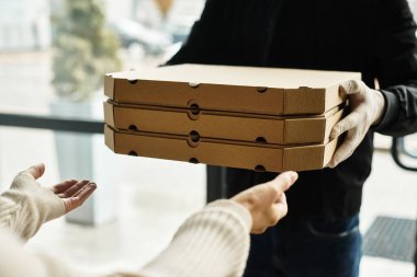 Teslimatçı kalabalık bir ofis ortamında birkaç yiyecek kutusu teslim eder..