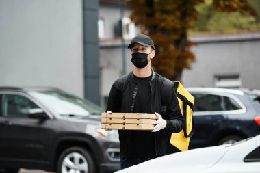Siyah maskeli bir teslimatçı ofis binasına yemek siparişi getirir ve personel için öğle yemeği molası verir..