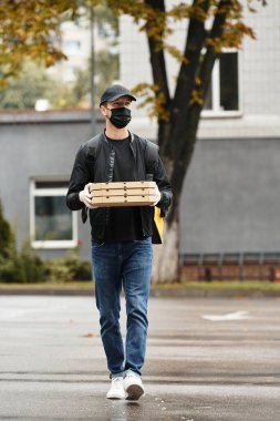 Bir kurye, elinde siyah bir maske ile bir sürü yemek siparişi taşıyarak bir ofis binasına girer..