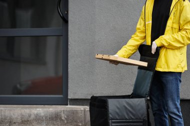 Siyah maskeli bir kurye bir ofis binasına gelir, yoğun çalışma alanı için paketlenmiş bir sipariş taşır..
