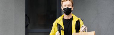 Siyah tıbbi maske takan bir teslimatçı bir ofis binasına güvenli teslimat için emir getirir..
