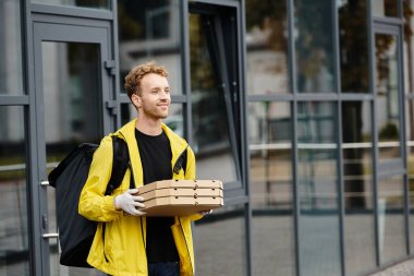 Teslimatçı gün ışığında ofise çoklu pizza kutusu taşır..