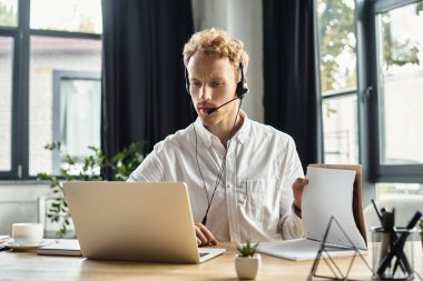 Kendini işine adamış kızıl saçlı bir işadamı modern ofis ortamında otururken bir projeye dahil oluyor..