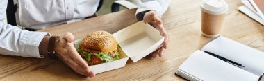 Proje üzerinde çalışırken beyaz gömlekli bir profesyonelin hamburgerin tadını çıkarması biraz zaman alır..