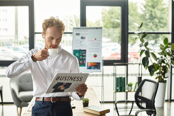 Рыжий бизнесмен в белой рубашке изучает бизнес-документ с кофе в современном рабочем пространстве.