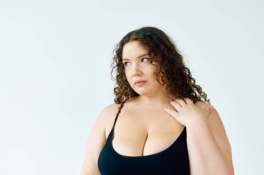 Güzel, iri yarı bir kadın zarif bir şekilde duruyor, özgüvenini ve eşsiz tarzını sergiliyor..