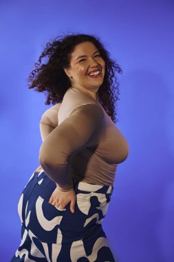 Çarpıcı, iri yarı bir kadın neşeli pozlar veriyor kıvrımlı siluetini ve canlı kişiliğini sergiliyor..