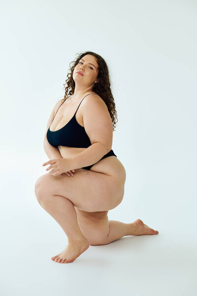 A beautiful plus size woman poses gracefully, showcasing confidence and self love in a studio.