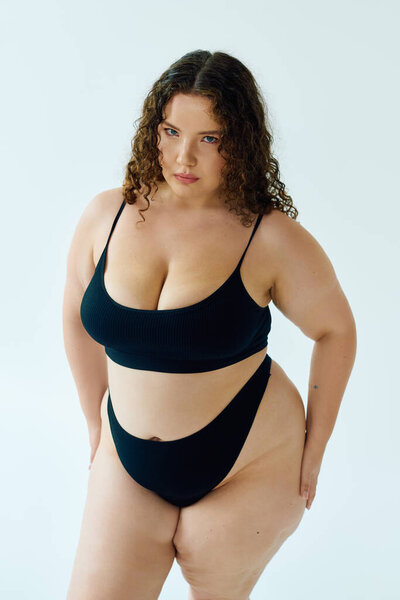 Уверенная в себе женщина plus size сияет в трикотажной черной одежде, демонстрируя потрясающую позу.