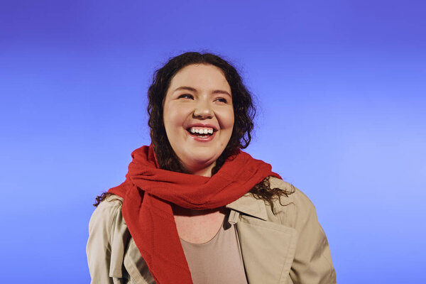 Красивая женщина plus size, одетая в стильный наряд, встречает момент с теплой улыбкой.