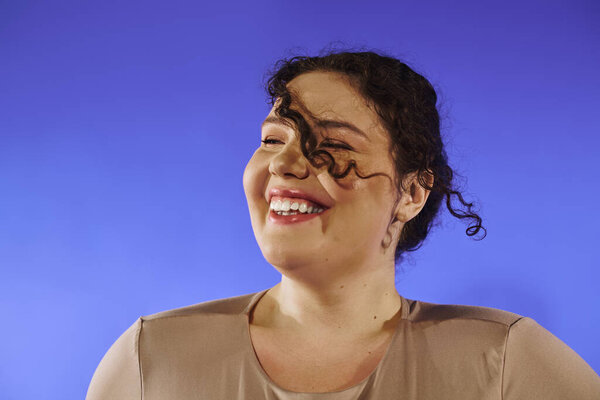 A confident plus size woman smiles brightly against a colorful backdrop.