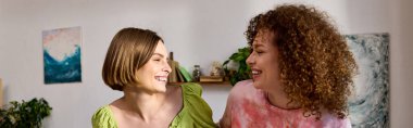 A delightful young lesbian couple shares laughter and love while relaxing indoors together. clipart