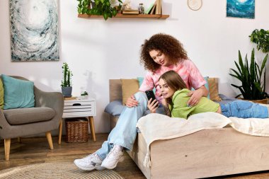 Two women share a tender moment, laughing and enjoying each others company in their home. clipart