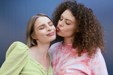 Two young women share a loving embrace, radiating joy and affection in a colorful setting. clipart