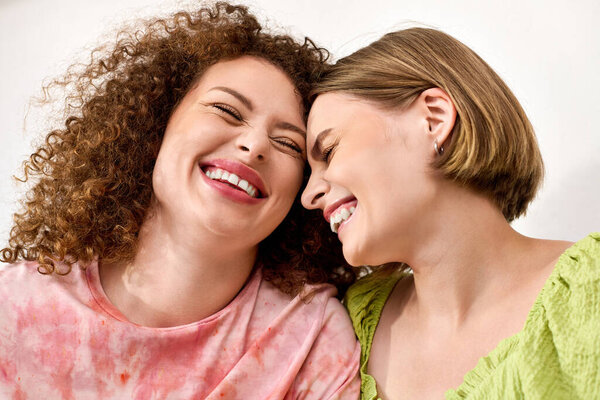 Two women laugh together, embracing each other with genuine joy in a warm atmosphere.