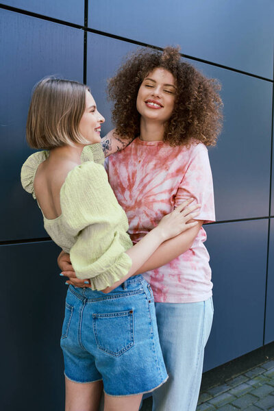 A beautiful young couple shares a warm embrace, laughing together in a cheerful atmosphere.