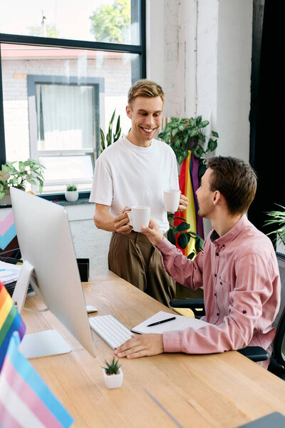 Двое счастливых мужчин делятся теплым обменом с кофейными чашками в ярком рабочем пространстве, заполненном растениями.
