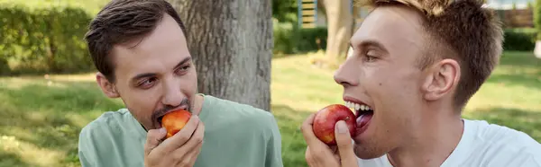 stock image A joyful couple shares a lighthearted moment, savoring apples together outdoors.