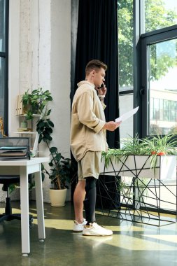 Protez bacaklı genç bir adam şık bir ofis alanında telefon görüşmesi yapıyor..