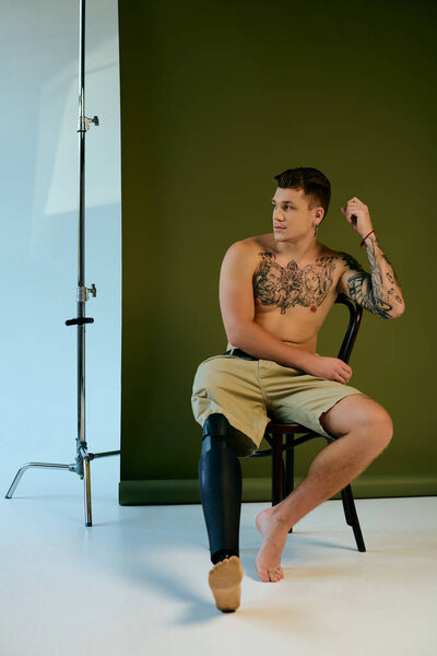 Молодой человек с яркими татуировками элегантно позирует в студии, принимая свой уникальный стиль и стойкость.
