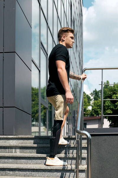 Решительный молодой человек поднимается на ступеньки современного кабинета, показывая свою протезную ногу с гордостью.