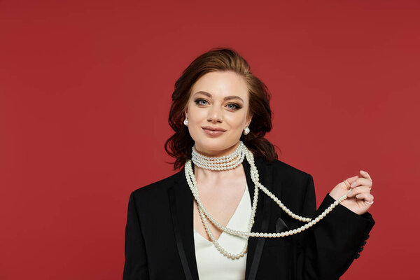 Dressed in elegant attire, the young woman confidently displays a stunning pearl necklace.