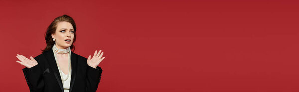 Элегантно одетая, молодая женщина источает уверенность, играя перед красным..