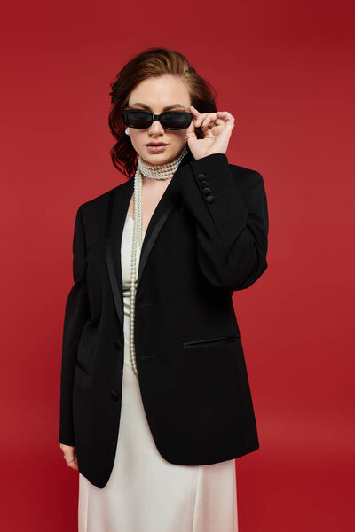 Одетый в сложный наряд, молодая женщина позирует уверенно, демонстрируя свой стиль.